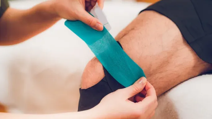 Kinesio tape being applied to a patient's knee