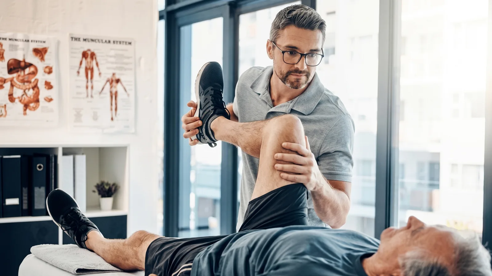 Physical therapist assisting a patient with a guided hip and leg stretch