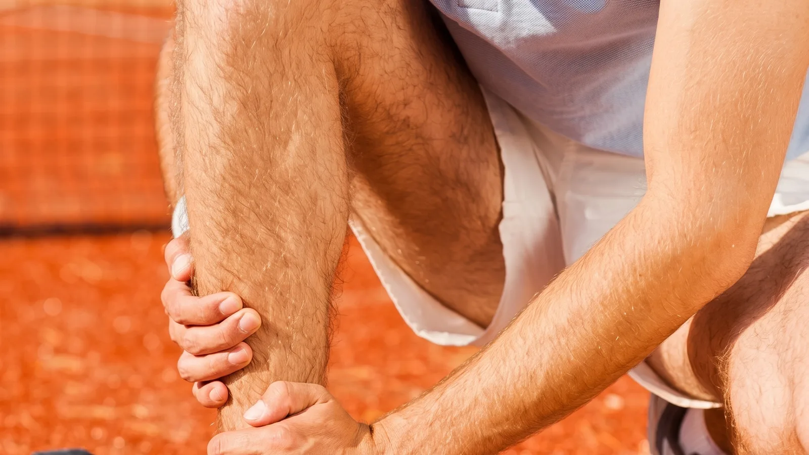 Athlete gripping an injured leg on an outdoor track