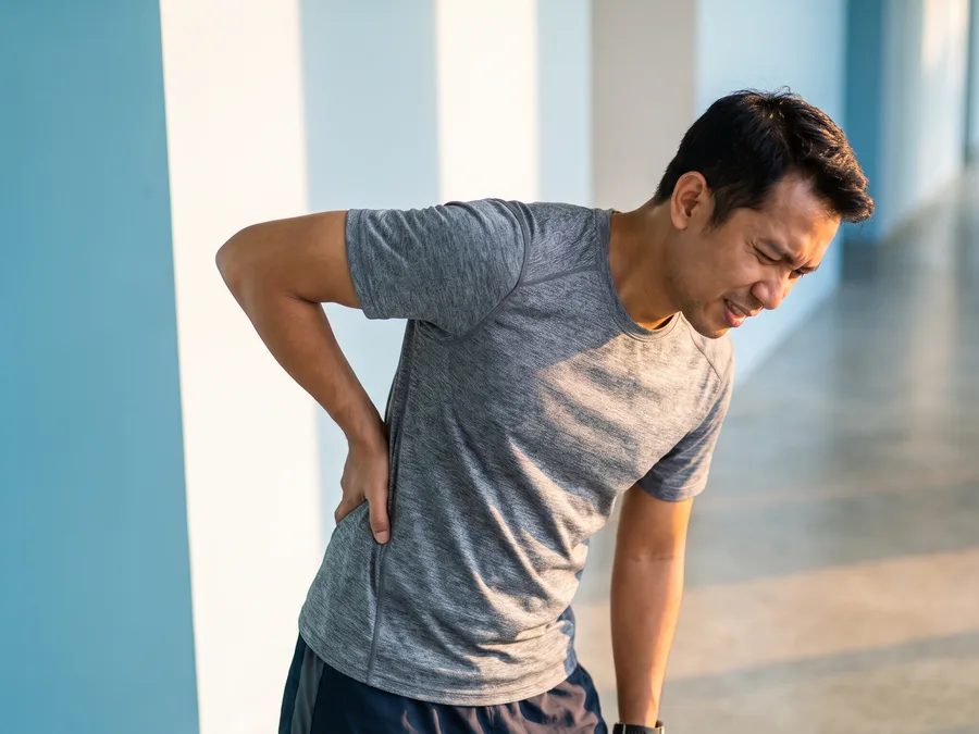 A man gripping his lower back in visible pain