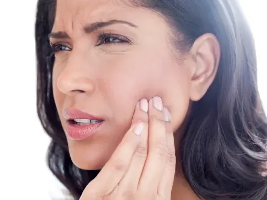 Woman touching her jaw in pain from TMJ/TMD